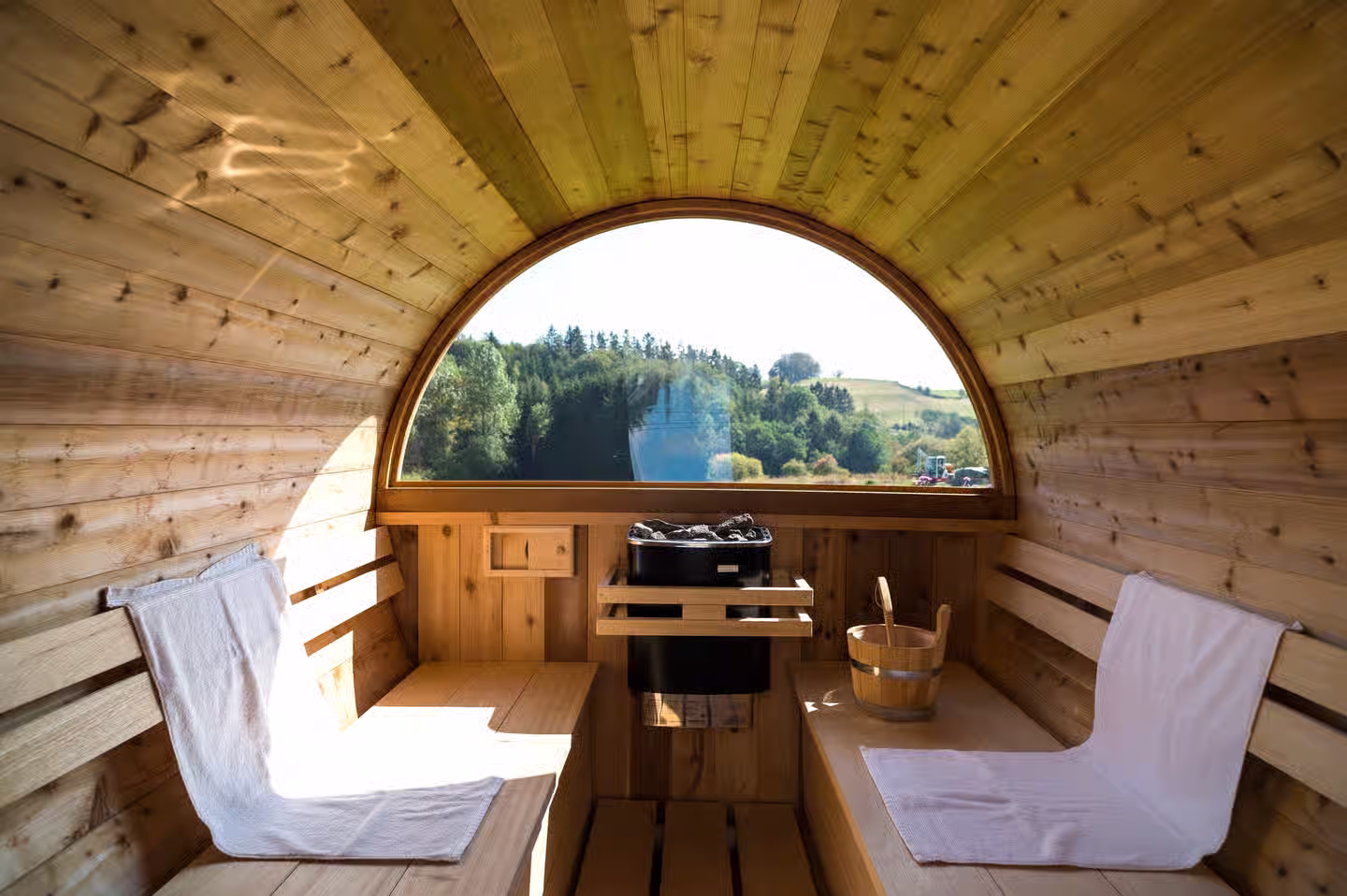 Sauna met uitzicht over een landschap met weiland en bossen